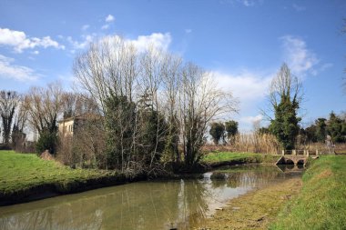Ağaçlı ve gökyüzü güneşli bir günde İtalya 'nın kırsal kesimlerinde suya dökülmüş.