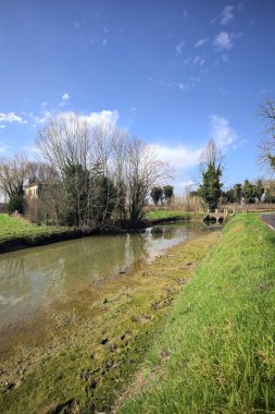 Ağaçlı ve gökyüzü güneşli bir günde İtalya 'nın kırsal kesimlerinde suya dökülmüş.