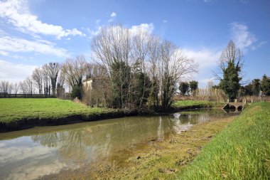 Ağaçlı ve gökyüzü güneşli bir günde İtalya 'nın kırsal kesimlerinde suya dökülmüş.