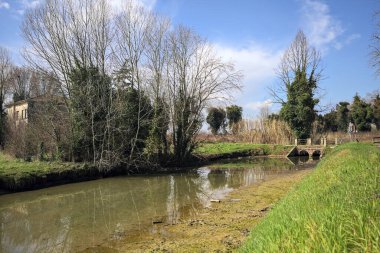 Ağaçlı ve gökyüzü güneşli bir günde İtalya 'nın kırsal kesimlerinde suya dökülmüş.