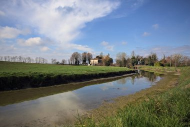 Ağaçlı ve gökyüzü güneşli bir günde İtalya 'nın kırsal kesimlerinde suya dökülmüş.