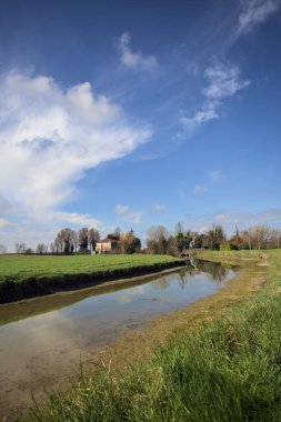 Ağaçlı ve gökyüzü güneşli bir günde İtalya 'nın kırsal kesimlerinde suya dökülmüş.