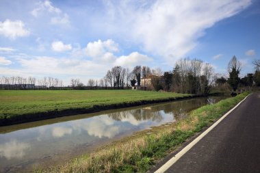 Ağaçlı ve gökyüzü güneşli bir günde İtalya 'nın kırsal kesimlerinde suya dökülmüş.
