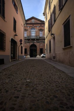 Bir İtalyan kasabasında tarihi bir sarayın ön cephesi ve kapısı olan gölgeli bir sokak.