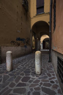Gölgedeki dar yol, bir İtalyan kasabasındaki verandanın başındaki kapalı bir geçitte sona eriyor.