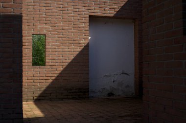 Parktaki tuğladan bir yapının ayrıntıları. Duvarda bir embriyo ve içinden görülebilen bir çimenlik.