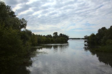 Güneşli bir günde, İtalya 'nın kırsal kesimlerinde ağaçların ve gökyüzünün olduğu bir nehrin körfezi.