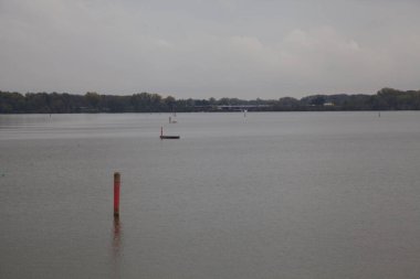 Gün batımında göl kenarına park et. Suda dökülen ağaçlar uzaktan görülebilir.