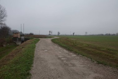 İtalya kırsalında bulutlu bir günde tarlalar arasındaki kirli yol