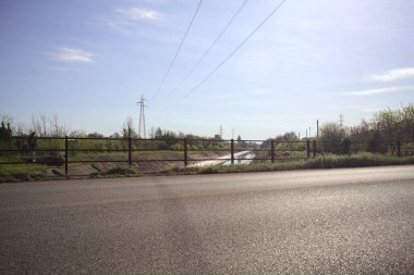 İtalya 'nın kırsal kesimindeki bir köprü tarafından çerçevelenen koruluklar arasında beton bir nehir yatağında oyalama kanalı.