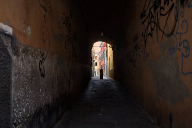 Duvarlarında grafiti olan dar bir sokak ve karşı ucunda da bir sütun var.