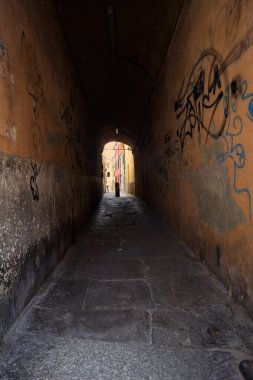 Duvarlarında grafiti olan dar bir sokak ve karşı ucunda da bir sütun var.