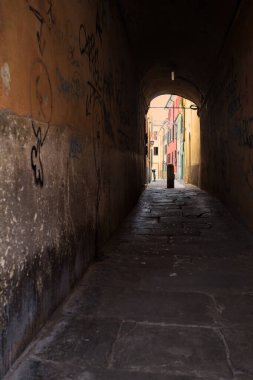 Duvarlarında grafiti olan dar bir sokak ve karşı ucunda da bir sütun var.