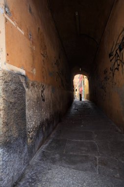 Duvarlarında grafiti olan dar bir sokak ve karşı ucunda da bir sütun var.