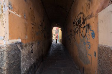 Duvarlarında grafiti olan dar bir sokak ve karşı ucunda da bir sütun var.