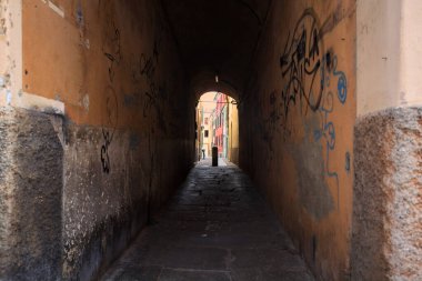 Duvarlarında grafiti olan dar bir sokak ve karşı ucunda da bir sütun var.