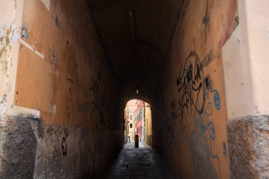 Duvarlarında grafiti olan dar bir sokak ve karşı ucunda da bir sütun var.