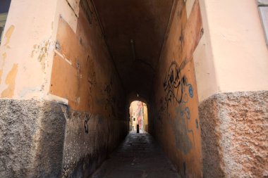 Duvarlarında grafiti olan dar bir sokak ve karşı ucunda da bir sütun var.