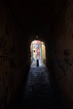 Duvarlarında grafiti olan dar bir sokak ve karşı ucunda da bir sütun var.