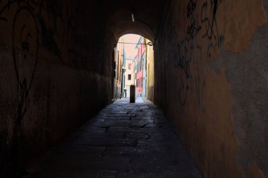 Duvarlarında grafiti olan dar bir sokak ve karşı ucunda da bir sütun var.