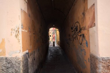 Duvarlarında grafiti olan dar bir sokak ve karşı ucunda da bir sütun var.