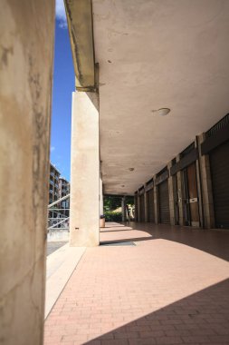 Gölgede veranda, İtalyan kasabasında bir sıra kavak ağacının yanında vitrinler.