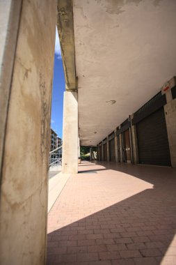 Gölgede veranda, İtalyan kasabasında bir sıra kavak ağacının yanında vitrinler.