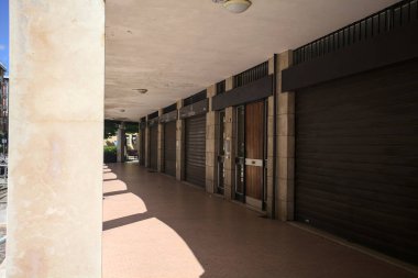 Gölgede veranda, İtalyan kasabasında bir sıra kavak ağacının yanında vitrinler.