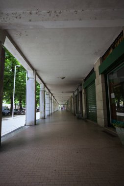 Gölgede veranda, İtalyan kasabasında bir sıra kavak ağacının yanında vitrinler.
