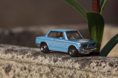 Mantova, İtalya - 27. Nisan 2025 - 1 / 64 Kibrit kutusu kopyası 1969 BMW 2002 bir bitkinin yaprağının altından geçen beton bir vazo üzerinde