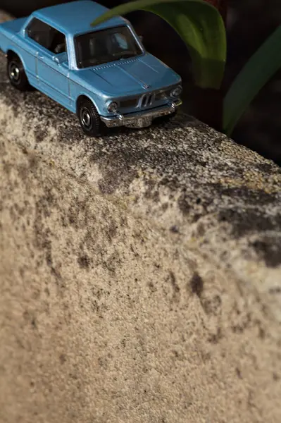 Mantova, İtalya - 27. Nisan 2025 - 1 / 64 Kibrit kutusu kopyası 1969 BMW 2002 bir bitkinin yaprağının altından geçen beton bir vazo üzerinde