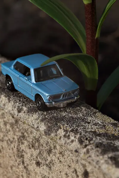 Mantova, İtalya - 27. Nisan 2025 - 1 / 64 Kibrit kutusu kopyası 1969 BMW 2002 bir bitkinin yaprağının altından geçen beton bir vazo üzerinde