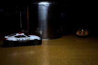 Mantova, İtalya - 29. Nisan 2025 - 1 / 64 Hot Wheels ve Takara Tomi kopyaları turuncu Nissan Fairlady Z ve Nissan Fairlady Z Nismo Japon polis arabası teneke bir oyuncak tencerenin yanında yol bariyeri simülasyonu yapıyor