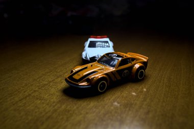 Mantova, İtalya - 29 Nisan 2025 - 1 / 64 Hot Wheels and Takara Tomi replicas of a orange Nissan Fairlady Z and a Nissan Fairlady Z Nismo Japanese police car simulating a ramming
