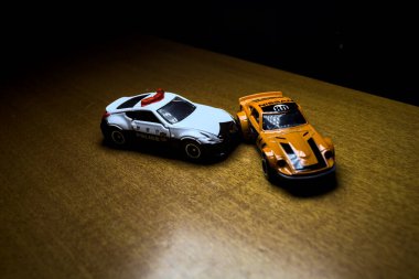 Mantova, İtalya - 29 Nisan 2025 - 1 / 64 Hot Wheels and Takara Tomi replicas of a orange Nissan Fairlady Z and a Nissan Fairlady Z Nismo Japanese police car simulating a ramming