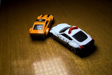 Mantova, İtalya - 29 Nisan 2025 - 1 / 64 Hot Wheels and Takara Tomi replicas of a orange Nissan Fairlady Z and a Nissan Fairlady Z Nismo Japanese police car simulating a ramming