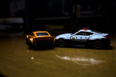 Mantova, İtalya - 29 Nisan 2025 - 1 / 64 Hot Wheels and Takara Tomi replicas of a orange Nissan Fairlady Z and a Nissan Fairlady Z Nismo Japanese police car simulating a ramming