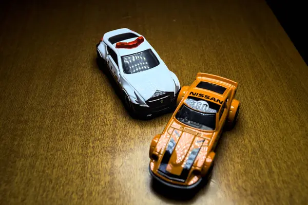 Mantova, İtalya - 29 Nisan 2025 - 1 / 64 Hot Wheels and Takara Tomi replicas of a orange Nissan Fairlady Z and a Nissan Fairlady Z Nismo Japanese police car simulating a ramming