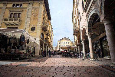 Mantova, İtalya - 8 Mart 2025 - Pazar tezgahları ve bulutlu bir günde kafelerin yanından geçen insanlar