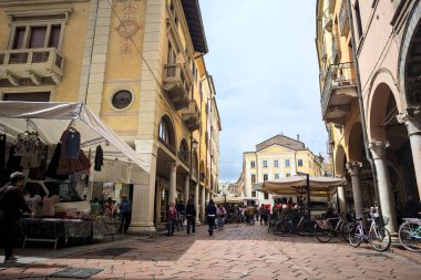 Mantova, İtalya - 8 Mart 2025 - Pazar tezgahları ve bulutlu bir günde kafelerin yanından geçen insanlar