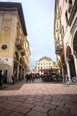 Mantova, İtalya - 8 Mart 2025 - Pazar tezgahları ve bulutlu bir günde kafelerin yanından geçen insanlar