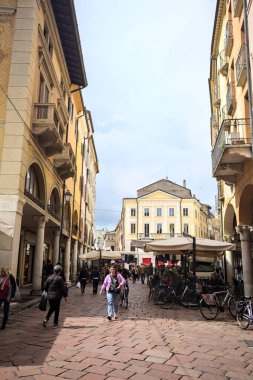 Mantova, İtalya - 8 Mart 2025 - Pazar tezgahları ve bulutlu bir günde kafelerin yanından geçen insanlar