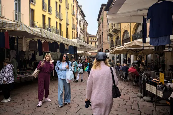 Mantova, İtalya - 8 Mart 2025 - Pazar tezgahları ve bulutlu bir günde kafelerin yanından geçen insanlar