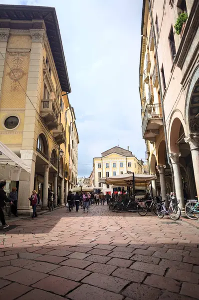 Mantova, İtalya - 8 Mart 2025 - Pazar tezgahları ve bulutlu bir günde kafelerin yanından geçen insanlar