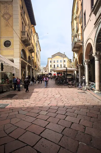 Mantova, İtalya - 8 Mart 2025 - Pazar tezgahları ve bulutlu bir günde kafelerin yanından geçen insanlar