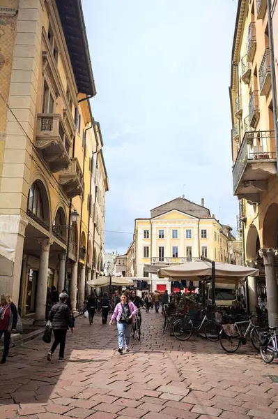 Mantova, İtalya - 8 Mart 2025 - Pazar tezgahları ve bulutlu bir günde kafelerin yanından geçen insanlar