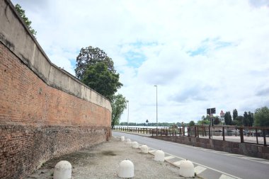 İtalya 'da bulutlu bir günde göl kıyısında tuğla bir duvarın yanındaki yol.