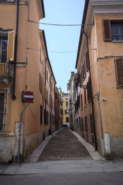 Gölgede dar kaldırımlar ve kenarlarında taş kaldırımlar olan dar bir cadde.