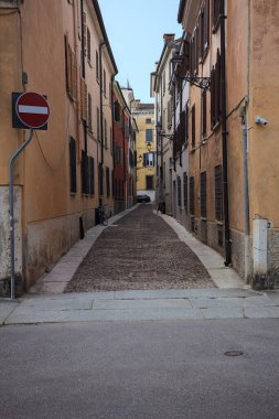 Gölgede dar kaldırımlar ve kenarlarında taş kaldırımlar olan dar bir cadde.