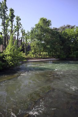 İtalya kırsalındaki nehir kıyısındaki bir malikanenin bahçesindeki merdivenler uzaktan görülüyor.